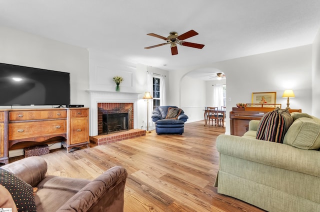 living room featuring ceiling fan, a fireplace, and light hardwood / wood-style flooring