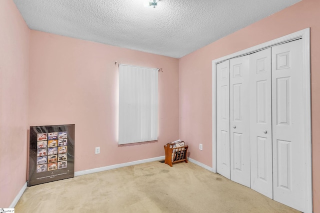 unfurnished bedroom with light colored carpet, a closet, and a textured ceiling