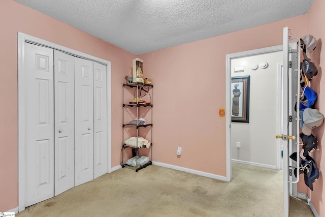 bedroom featuring light carpet, a closet, and a textured ceiling