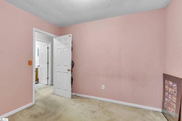 unfurnished room with light carpet and a textured ceiling