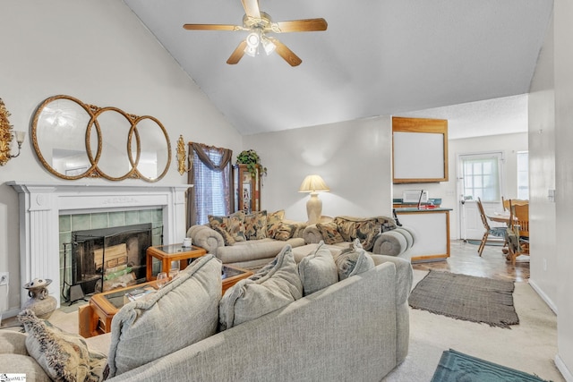 living room featuring high vaulted ceiling, light colored carpet, a tile fireplace, and ceiling fan