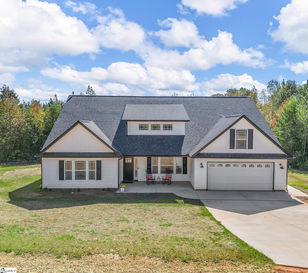 view of front facade with a garage, a front yard, and a patio