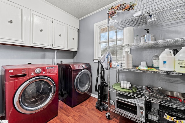 clothes washing area with cabinets, washing machine and clothes dryer, light hardwood / wood-style floors, crown molding, and a textured ceiling