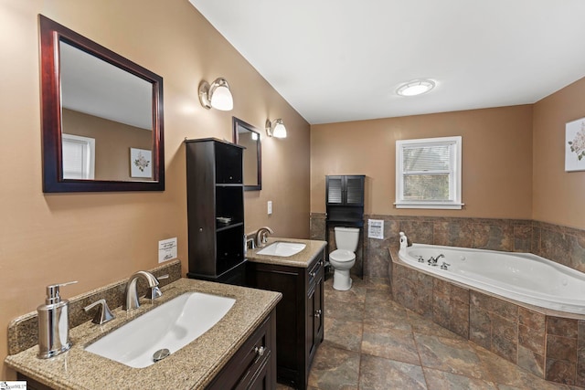 bathroom featuring vanity, a relaxing tiled tub, and toilet