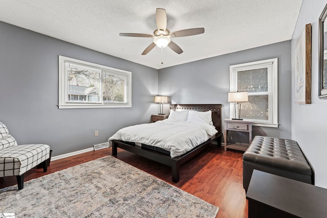 bedroom featuring ceiling fan, dark wood-type flooring, and a textured ceiling