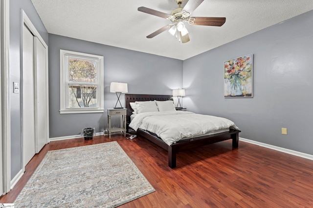 bedroom featuring ceiling fan, a closet, dark hardwood / wood-style flooring, and a textured ceiling