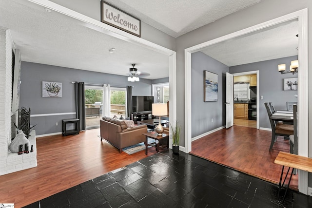 living room with dark hardwood / wood-style floors, ceiling fan with notable chandelier, and a textured ceiling