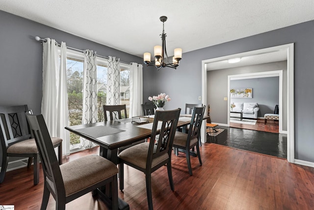 dining area with dark wood-type flooring, a chandelier, and a textured ceiling