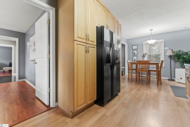 kitchen featuring light hardwood / wood-style flooring, hanging light fixtures, black refrigerator with ice dispenser, and a textured ceiling