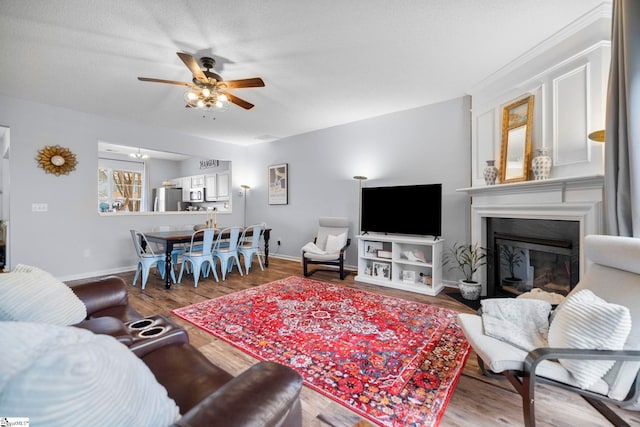 living room featuring ceiling fan, wood-type flooring, and a textured ceiling