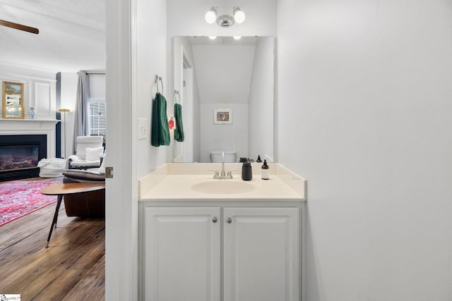 bathroom with wood-type flooring, vanity, ceiling fan, and toilet