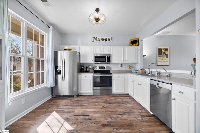 kitchen with dark wood-type flooring, stainless steel appliances, sink, and white cabinets