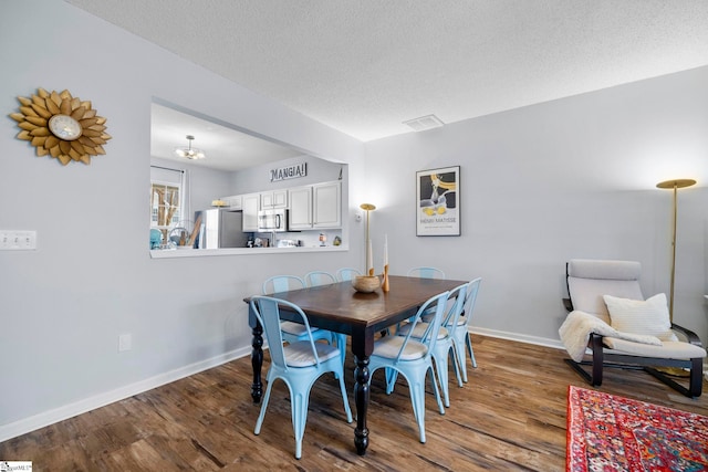 dining area featuring hardwood / wood-style flooring, a textured ceiling, and a notable chandelier