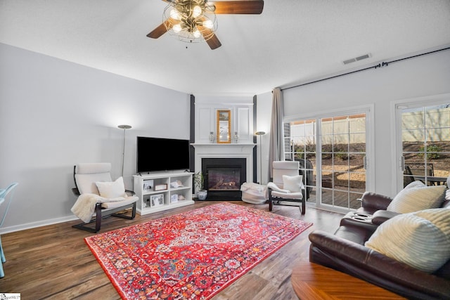 living room with hardwood / wood-style flooring, ceiling fan, and a textured ceiling