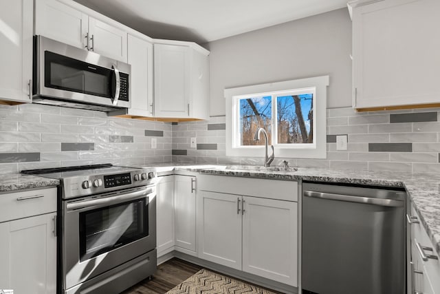 kitchen featuring light stone counters, stainless steel appliances, sink, and white cabinets