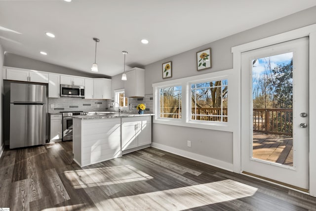 kitchen featuring appliances with stainless steel finishes, white cabinetry, hanging light fixtures, light stone countertops, and kitchen peninsula