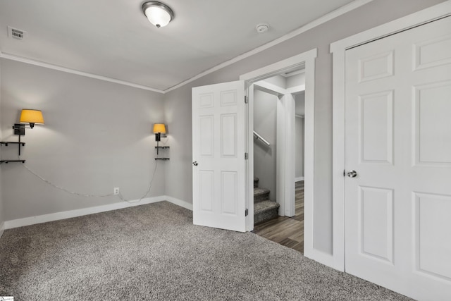 unfurnished bedroom featuring crown molding and dark carpet