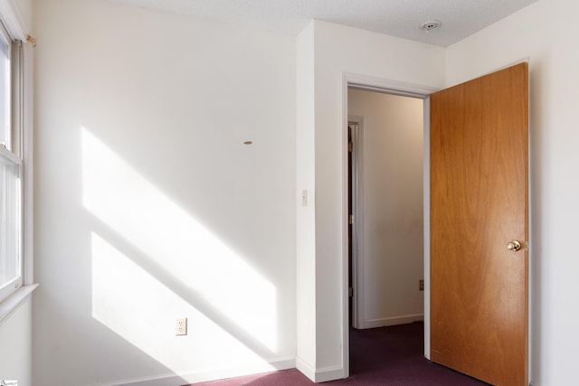 spare room with dark carpet and a textured ceiling