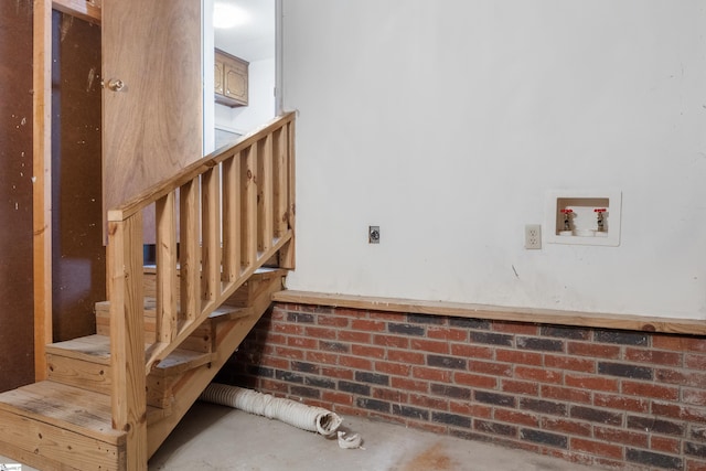 staircase with concrete floors and brick wall