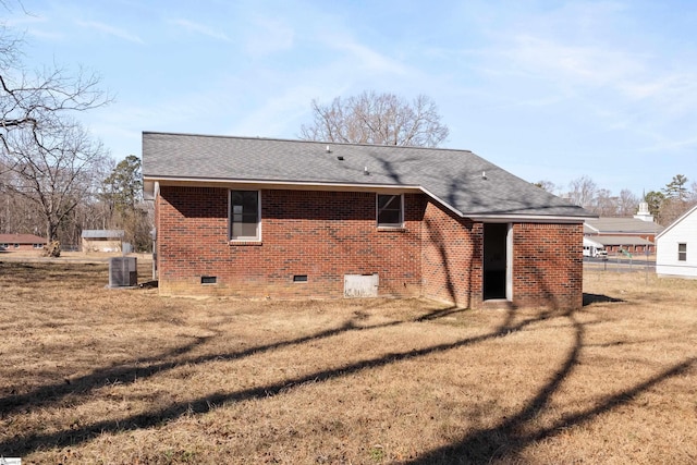 rear view of house featuring central AC unit and a lawn