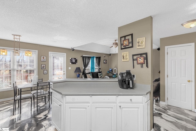 kitchen with a center island, pendant lighting, white cabinets, and a textured ceiling