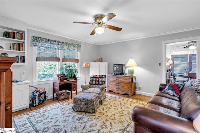 living room with ceiling fan, ornamental molding, and light wood-type flooring