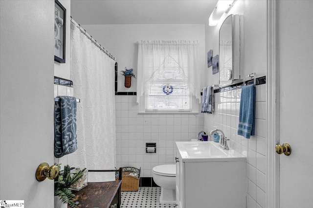 bathroom featuring vanity, tile walls, and toilet