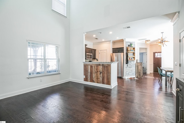 unfurnished living room with a high ceiling, ornamental molding, a notable chandelier, and dark hardwood / wood-style flooring