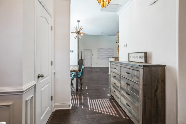 hallway with ornamental molding, dark hardwood / wood-style floors, and a notable chandelier