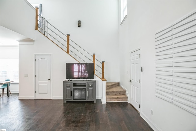 unfurnished living room with dark wood-type flooring, a healthy amount of sunlight, and a high ceiling