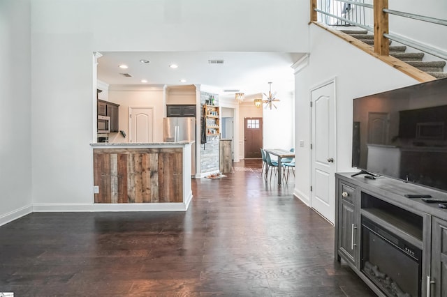 kitchen with crown molding, appliances with stainless steel finishes, dark wood-type flooring, and an inviting chandelier