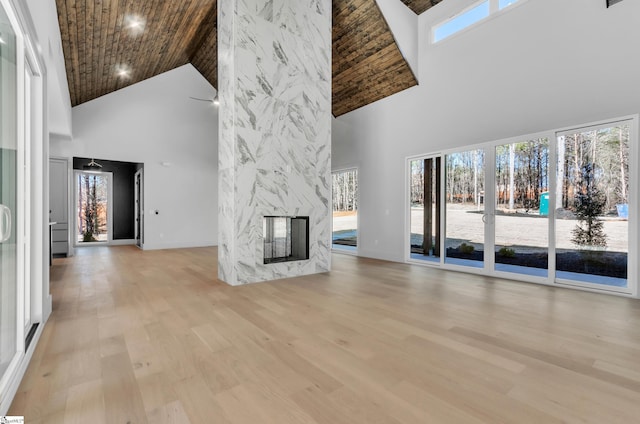 unfurnished living room with plenty of natural light, light wood-type flooring, a fireplace, and wood ceiling