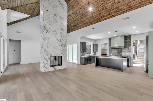 kitchen with hanging light fixtures, a center island, a fireplace, and a towering ceiling