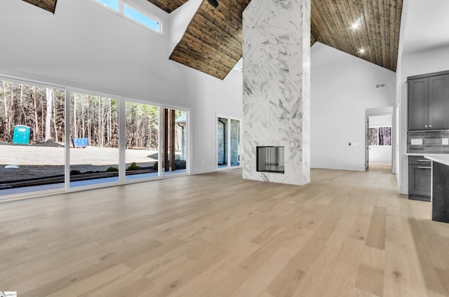 unfurnished living room with a high end fireplace, a high ceiling, and light wood-type flooring