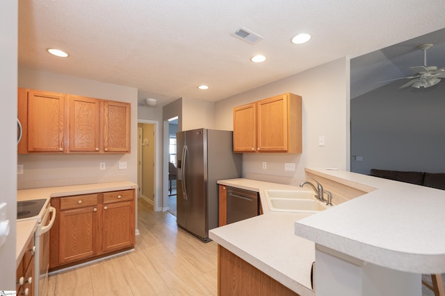 kitchen with sink, appliances with stainless steel finishes, a kitchen breakfast bar, kitchen peninsula, and ceiling fan