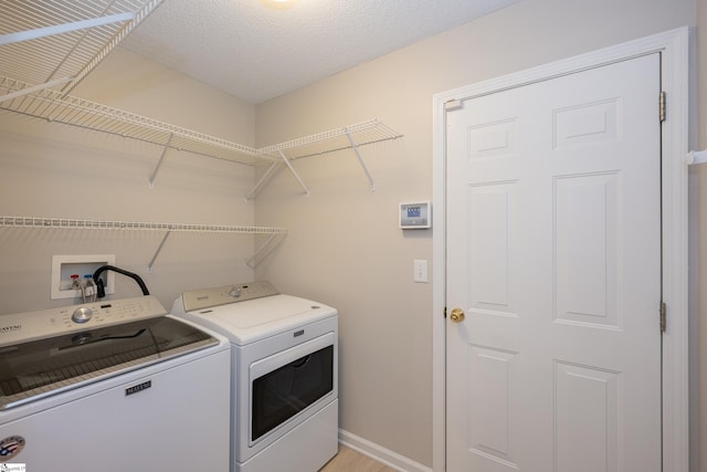 clothes washing area featuring separate washer and dryer and a textured ceiling