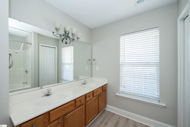 bathroom featuring hardwood / wood-style flooring, shower / bathtub combination, vanity, and an inviting chandelier