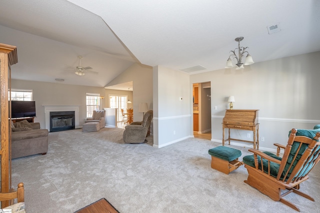 living room featuring ceiling fan with notable chandelier, vaulted ceiling, and light carpet