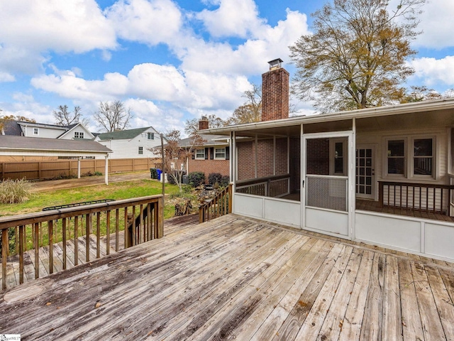 wooden deck featuring a sunroom and a lawn