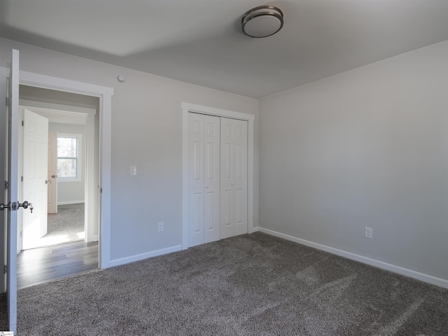 unfurnished bedroom with dark carpet and a closet