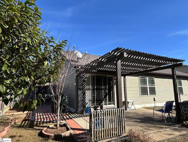 rear view of property featuring a pergola and a patio area