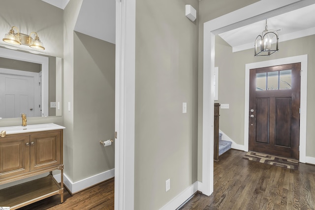 entrance foyer with dark wood-type flooring, sink, and a chandelier