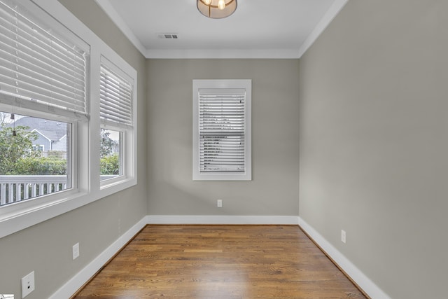 empty room featuring wood-type flooring and ornamental molding