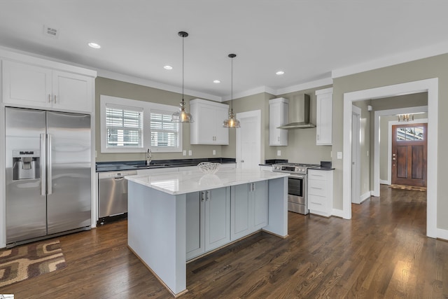 kitchen featuring appliances with stainless steel finishes, a center island, white cabinets, and wall chimney exhaust hood