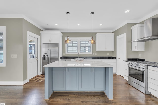 kitchen with a center island, wall chimney range hood, pendant lighting, stainless steel appliances, and white cabinets