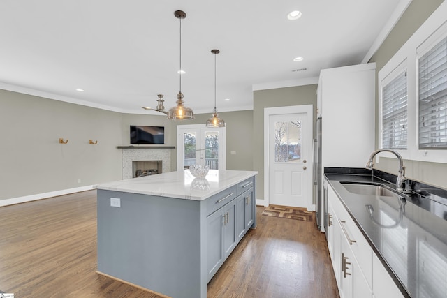 kitchen featuring pendant lighting, crown molding, white cabinetry, light stone counters, and dark hardwood / wood-style flooring