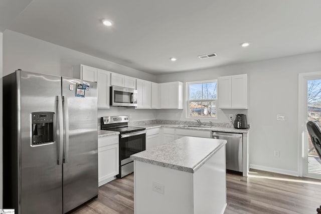 kitchen with appliances with stainless steel finishes, a center island, sink, and white cabinets