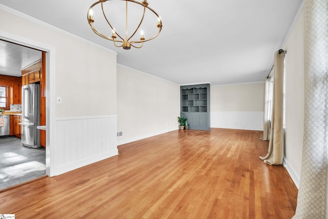 spare room featuring crown molding, light hardwood / wood-style floors, and a chandelier