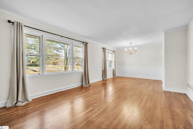 spare room featuring crown molding, a baseboard heating unit, an inviting chandelier, and light hardwood / wood-style floors