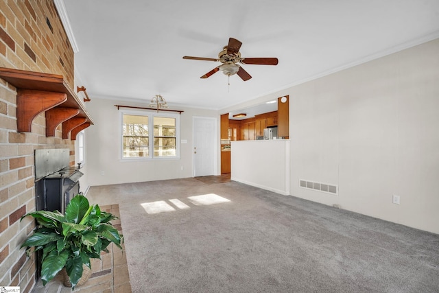 unfurnished living room with crown molding, ceiling fan, light carpet, and a brick fireplace